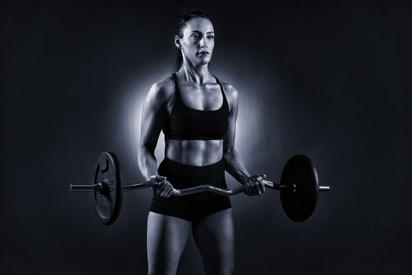 Monochrome toned image of an athletic woman doing barbell biceps curls