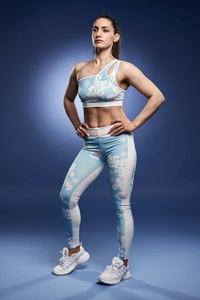 Mladá Atletická Žena Pózující Modrém Pozadí Tělocvičně — Stock fotografie