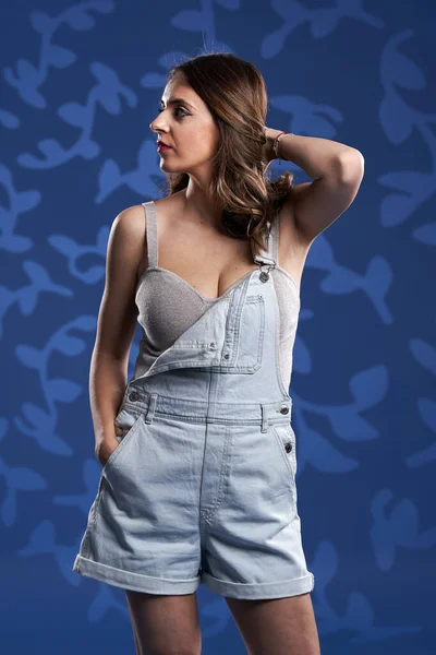 Happy Young Woman Denim Overalls Studio Shot Blue Floral Background — Photo