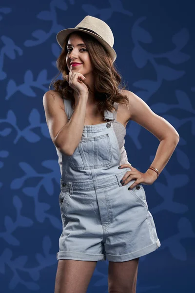 穿着粗斜纹棉布工作服的年轻漂亮女人 衬托着蓝色的花朵背景 演播室的镜头 — 图库照片