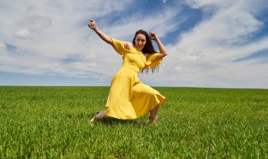 Yeşil bir çayırda aptalca hareketler yapan komik genç kadın.