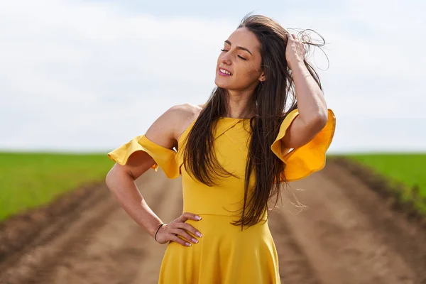 在麦田的土路上 穿着黄色衣服的年轻女子 — 图库照片