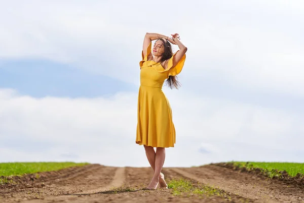 Sarı Elbiseli Çıplak Ayaklı Genç Kadın Buğday Tarlalarının Arasında Toprak — Stok fotoğraf