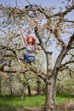 Kıvırcık kızıl saçlı çiftçi kadın elma bahçesinde çiçek açmış.