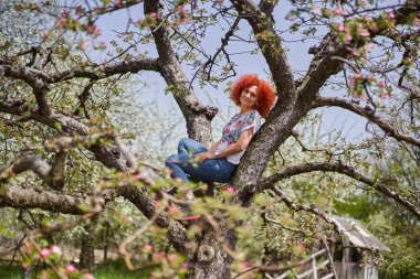 Kıvırcık kızıl saçlı çiftçi kadın elma bahçesinde çiçek açmış.