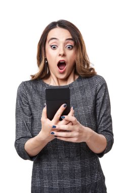 Çok şaşırmış bir ifadeyle, beyaz arka planda izole edilmiş akıllı telefonuna bakan bir iş kadını.