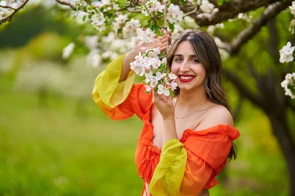 在苹果园里穿着橘色长裙的美丽的印度姑娘 — 图库照片