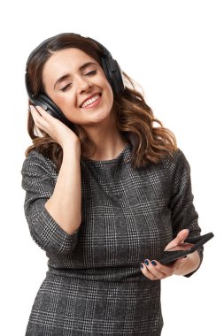 Kulaklıklı genç bir iş kadını. Akıllı telefonundan müzik dinliyor ve dans ediyor. Beyaz arka planda izole edilmiş.