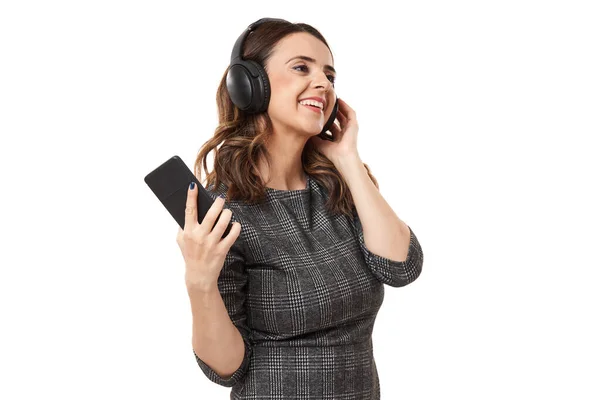 年轻的女商人带着耳机 一边听着智能手机里的音乐 一边跳舞 被白色背景隔离着 — 图库照片