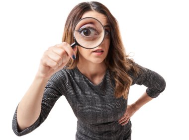 Closeup of a businesswoman looking at camera through a magnifier clipart