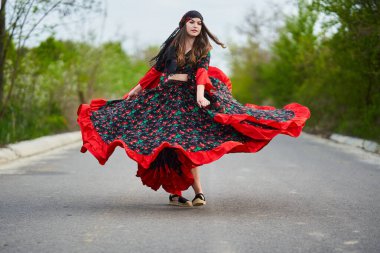 Caddenin ortasında dans eden genç, güzel çingene kadın, geleneksel kostümlü.