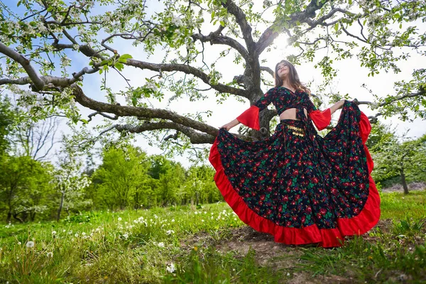 伝統的なジプシーのドレスを着た若い女性がリンゴ園で踊り — ストック写真