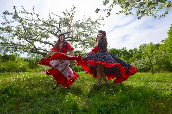 Två Unga Kvinnor Traditionell Zigenardräkt Dansar Blommande Äppelträdgård — Stockfoto