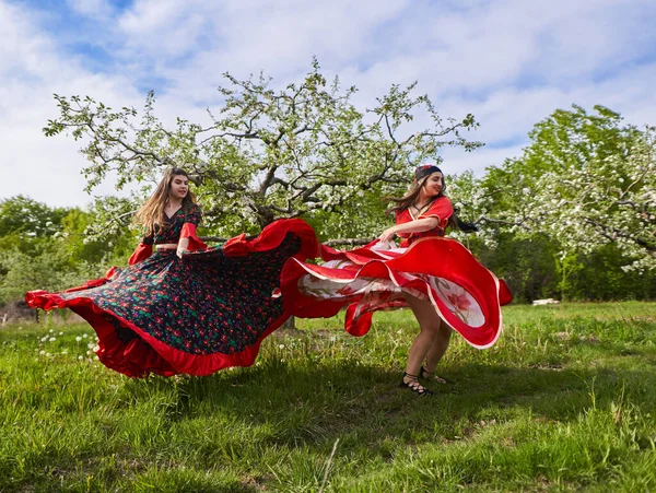 Twee Jonge Vrouwen Traditioneel Zigeunerkostuum Dansen Een Bloeiende Appelboomgaard — Stockfoto