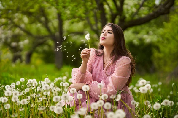 在果园里的年轻女子 随风飘扬的蒲公英种子 — 图库照片