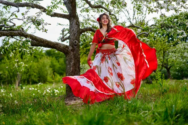 伝統的なジプシーのドレスを着た若い女性がリンゴ園で踊り — ストック写真