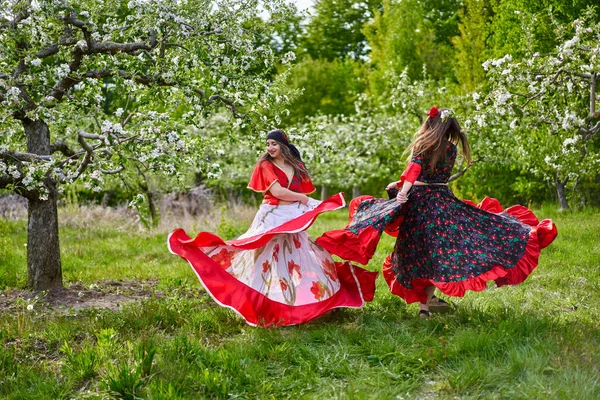 Две Молодые Девушки Традиционном Цыганском Костюме Танцуют Цветущем Яблочном Саду — стоковое фото