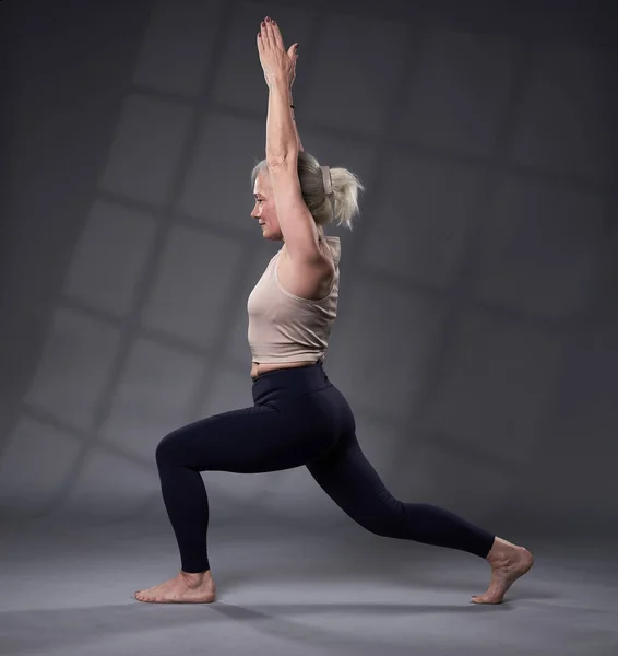 白い髪の訓練ヨガとシニア女性 スタジオショット上の灰色の背景 — ストック写真