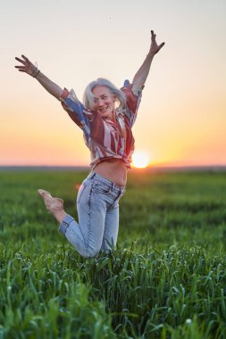 Gün batımında buğday tarlasında beyaz saçlı yaşlı bir çiftçi kadının portresi.