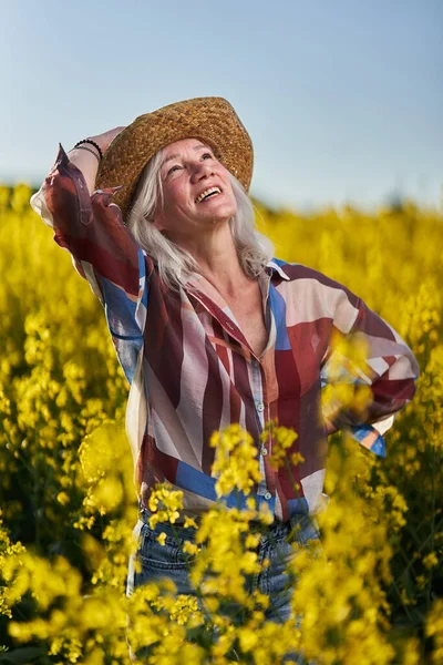 美しいですシニア女性白い髪で菜の花畑 — ストック写真