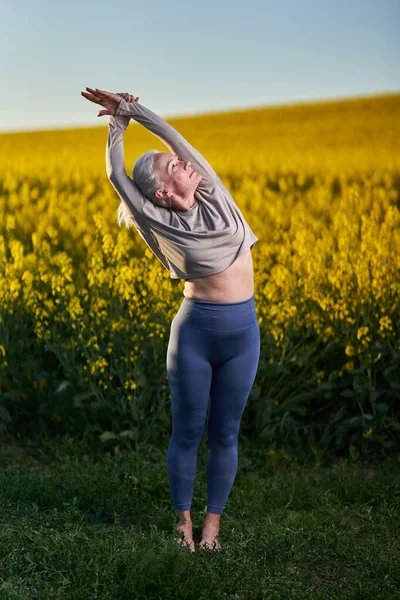 Senior Kvinna Med Vitt Hår Gör Yoga Träning Canola Fält — Stockfoto