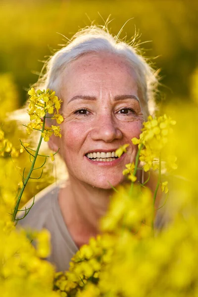 美しいですシニア女性白い髪で菜の花畑 — ストック写真