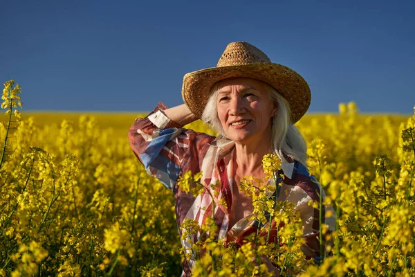 美しいですシニア女性白い髪で菜の花畑 — ストック写真