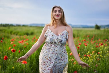 Haşhaş tarlasında çiçek desenli elbiseler giyen güzel, iri yarı Hintli bir kadın.