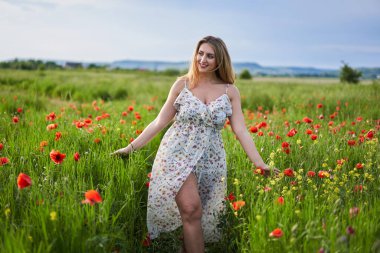 Haşhaş tarlasında çiçek desenli elbiseler giyen güzel, iri yarı Hintli bir kadın.