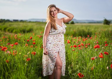 Haşhaş tarlasında çiçek desenli elbiseler giyen güzel, iri yarı Hintli bir kadın.