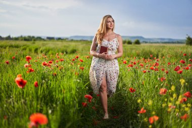 Haşhaş tarlasında çiçek desenli elbiseler giyen güzel, iri yarı Hintli bir kadın.