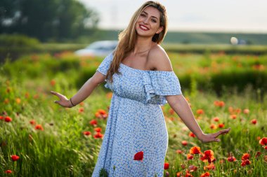 Haşhaş tarlasında çiçek desenli elbiseler giyen güzel, iri yarı Hintli bir kadın.