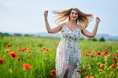 Haşhaş tarlasında çiçek desenli elbiseler giyen güzel, iri yarı Hintli bir kadın.