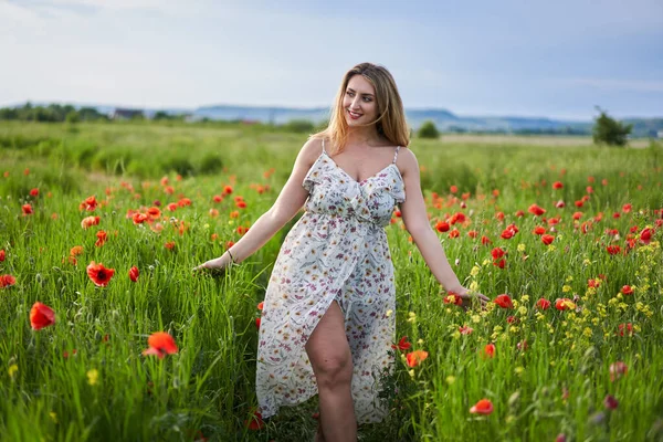 Haşhaş tarlasında çiçek desenli elbiseler giyen güzel, iri yarı Hintli bir kadın.