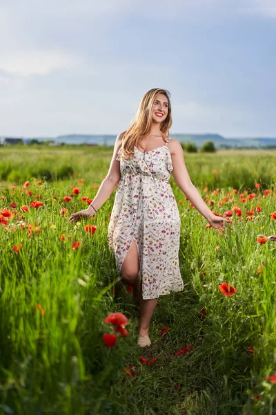 Haşhaş tarlasında çiçek desenli elbiseler giyen güzel, iri yarı Hintli bir kadın.