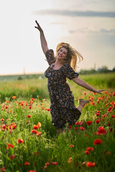 Haşhaş tarlasında çiçek desenli elbiseler giyen güzel, iri yarı Hintli bir kadın.