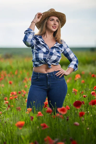 美しいプラスサイズ農家の女性で再生シャツ ジーンズとケシ畑で帽子 — ストック写真
