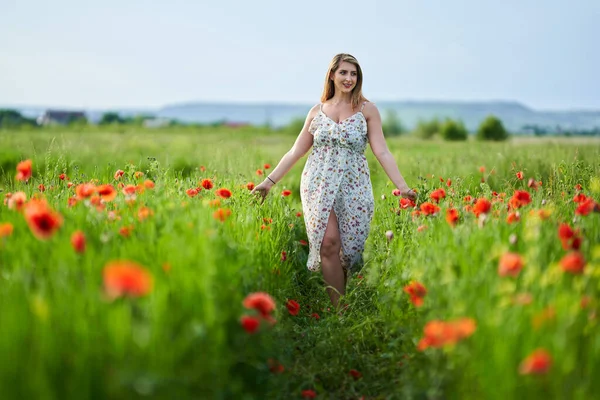 Haşhaş tarlasında çiçek desenli elbiseler giyen güzel, iri yarı Hintli bir kadın.