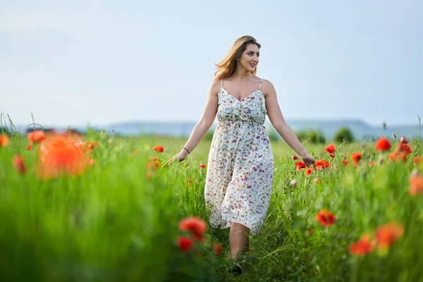 Haşhaş tarlasında çiçek desenli elbiseler giyen güzel, iri yarı Hintli bir kadın.