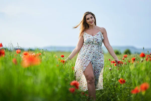 Haşhaş tarlasında çiçek desenli elbiseler giyen güzel, iri yarı Hintli bir kadın.