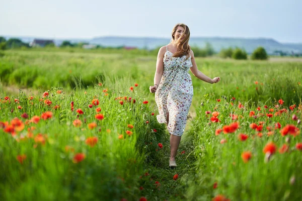 Haşhaş tarlasında çiçek desenli elbiseler giyen güzel, iri yarı Hintli bir kadın.