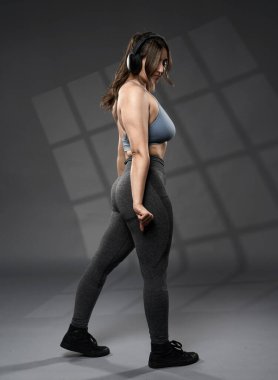 Güçlü beden ölçüleri ve gri arka planda ağırlık çalışan Hintli kadın.