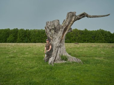 Kamuflaj giymiş, meşe ormanında büyük bir kütük tarafından av korucusu.