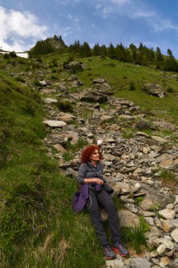 Kadın fotoğrafçı, kamerasıyla dağlarda yürüyüş yapıyor.