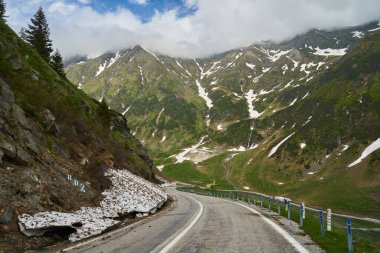 Yazın başında yüksek dağların arasında asfalt bir yol var.