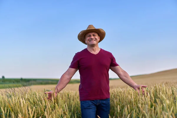 田舎の熟した小麦畑を歩くわら帽子の農家 — ストック写真