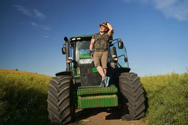 農夫は菜種畑でトラクターと一緒に — ストック写真