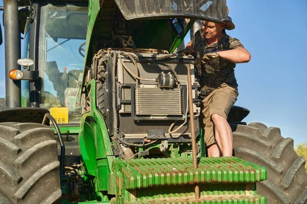 农场主试图修理他在油菜田中央的破拖拉机 免版税图库图片