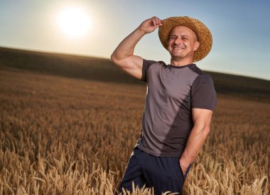 Olgun bir buğday tarlasında gün batımında mutlu bir çiftçi