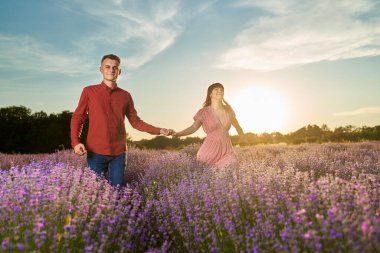 Gün batımında lavanta tarlasında harika vakit geçiren genç bir çift.